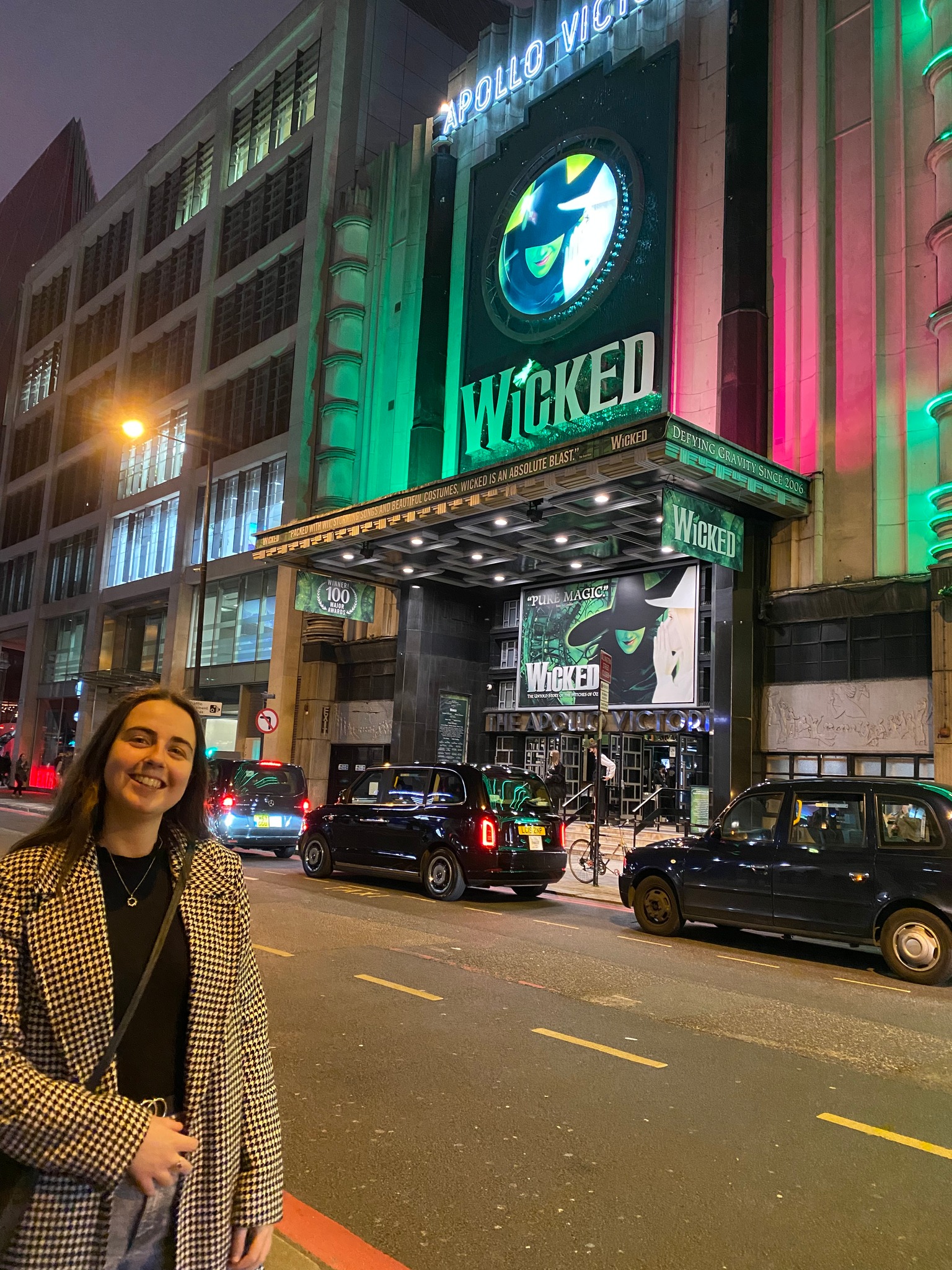 A girl standing in front of the Apollo Victoria Theatre where 'Wicked' plays