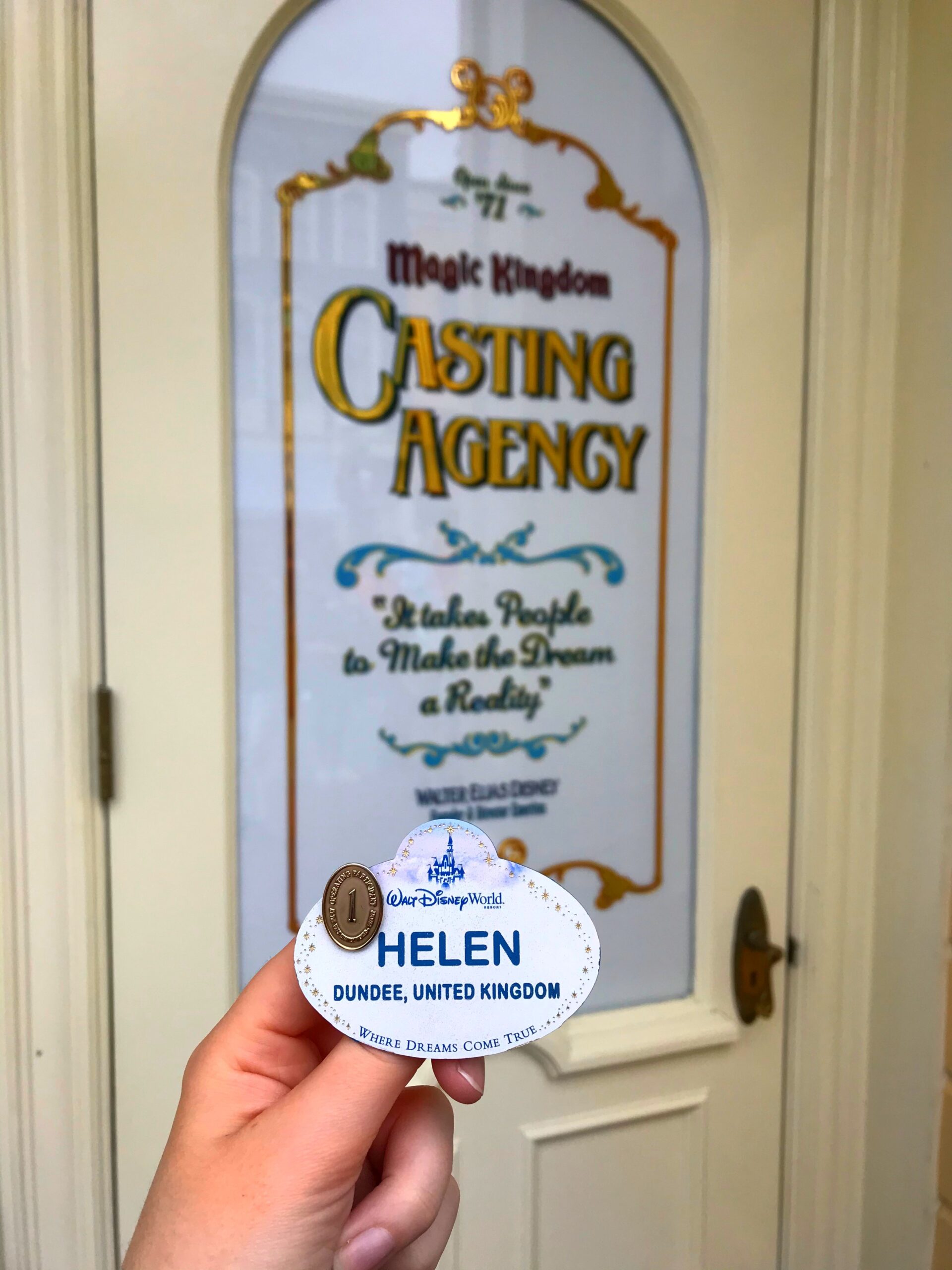 Cast member name tag with the name 'Helen' from 'Dundee, United Kingdom' in front of a door that says 'Casting Agency'